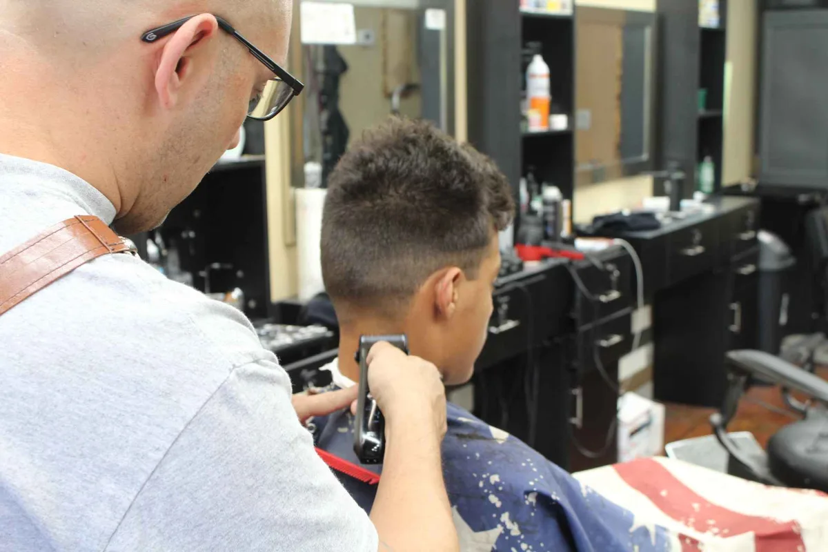 A barber working with clippers at a chair inside the studio