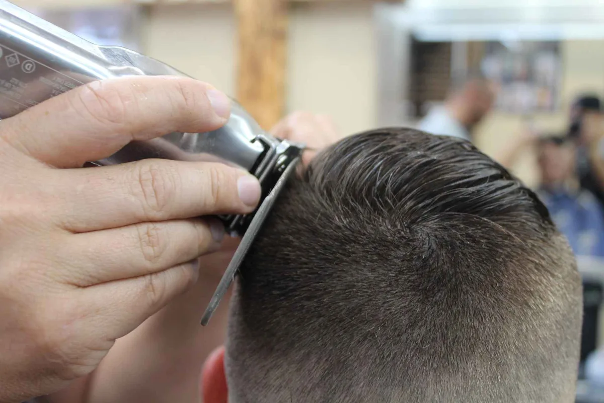 Clippers and comb working on the side of a haircut