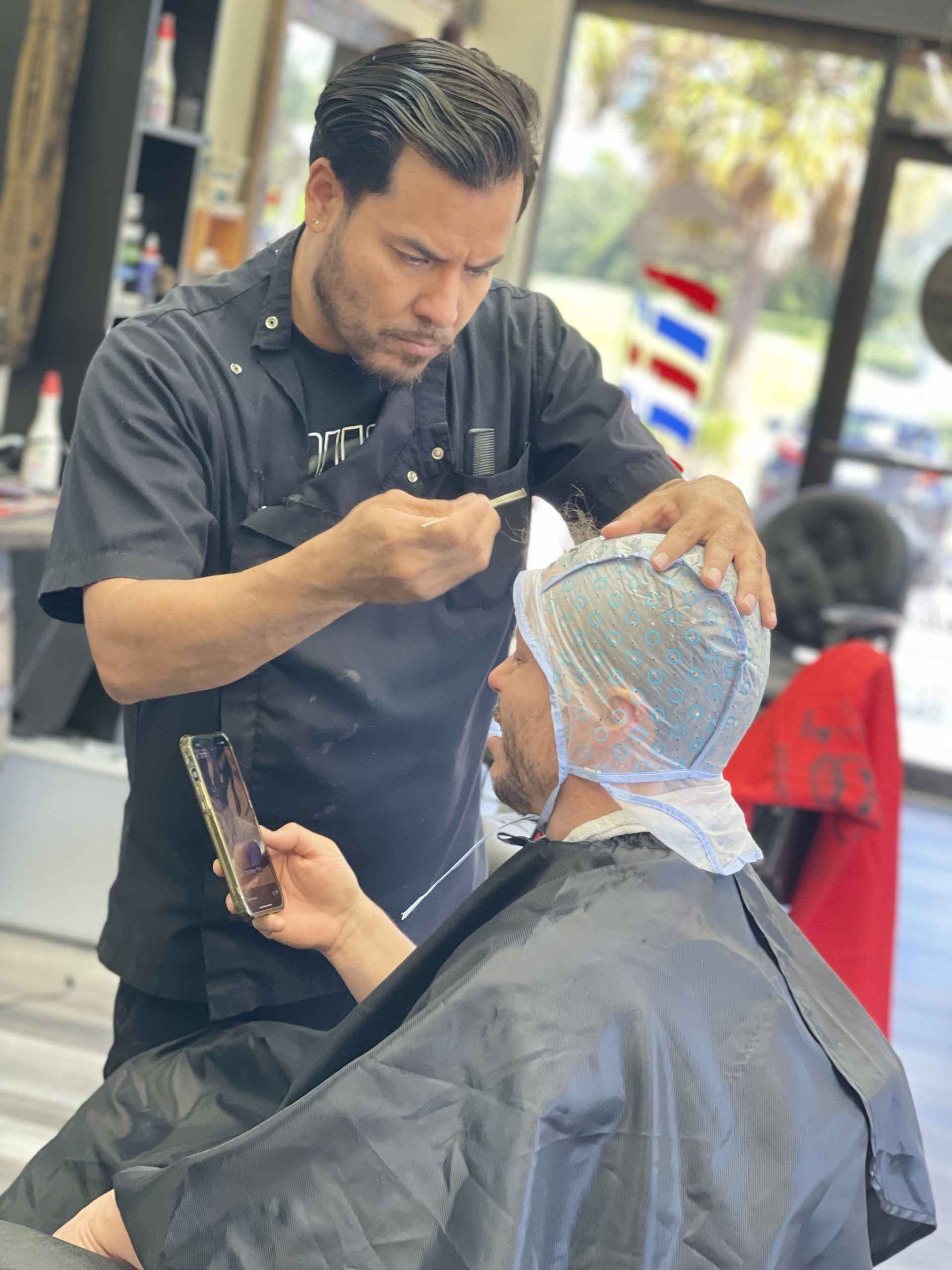 A barber working through a highlighting cap during a color service