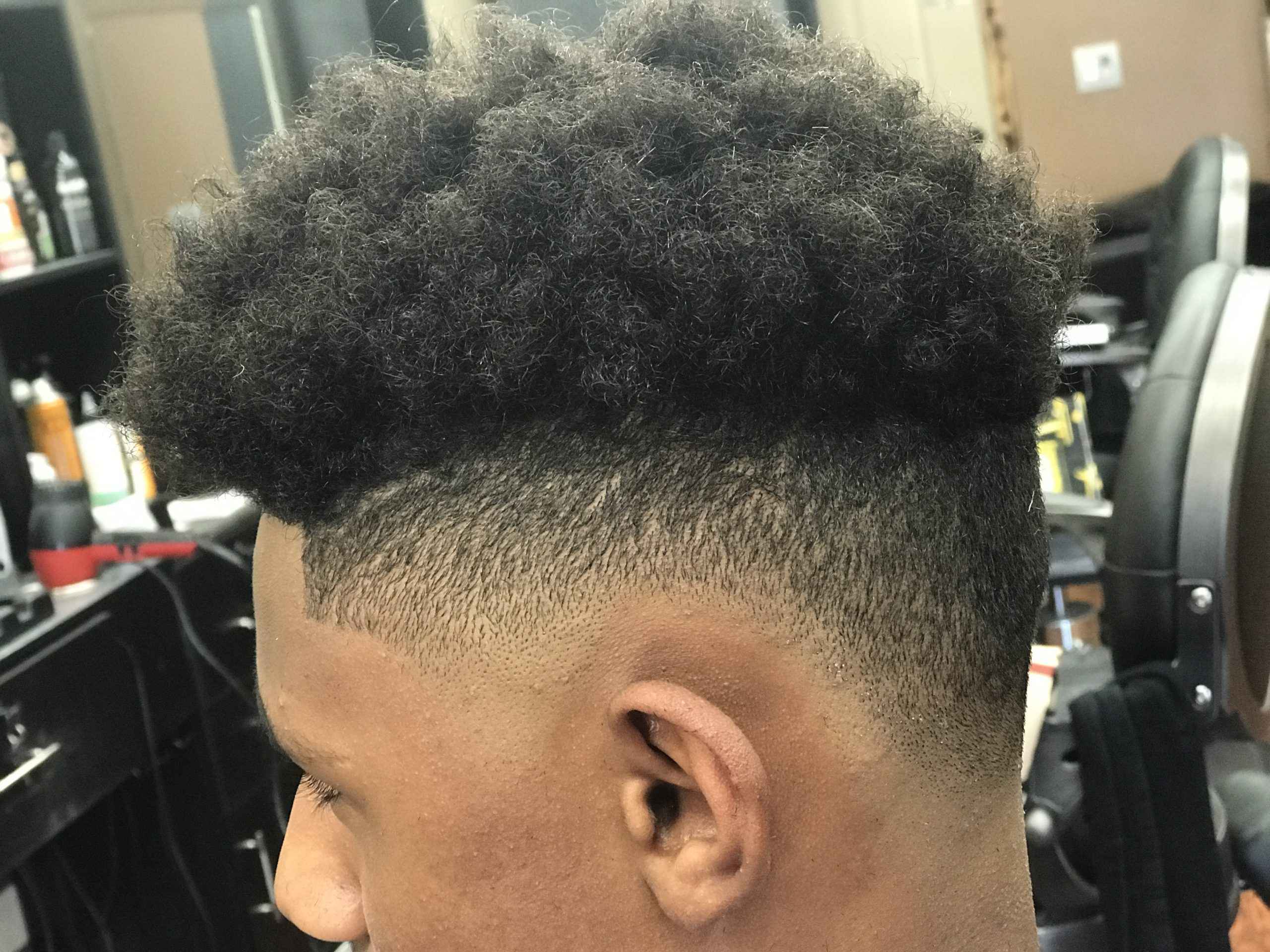 Close side view of a high-top fade with a curly top