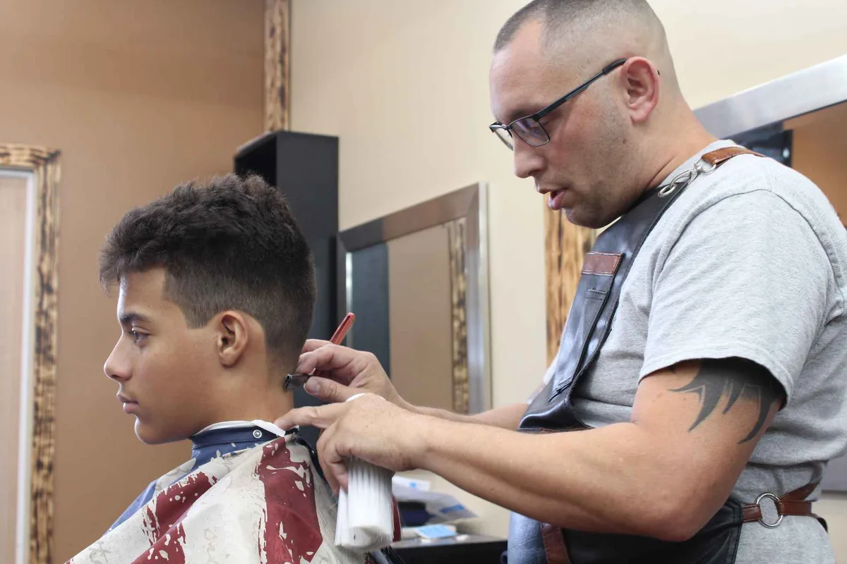 A barber finishing a client’s neckline