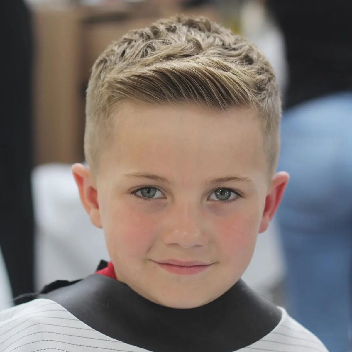 A young client in a barber cape with a fresh short textured cut