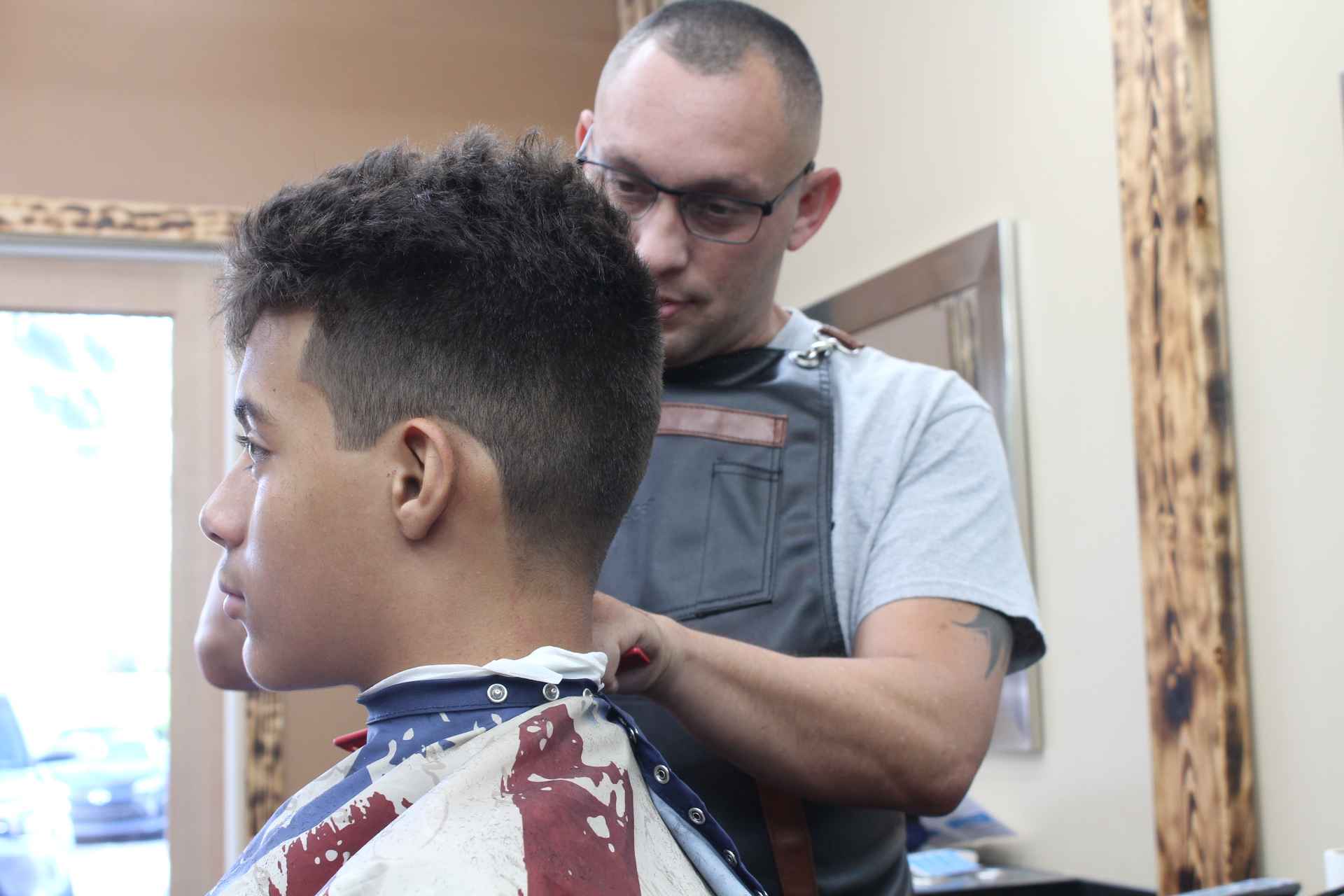 A barber finishing a young client’s taper at the neck